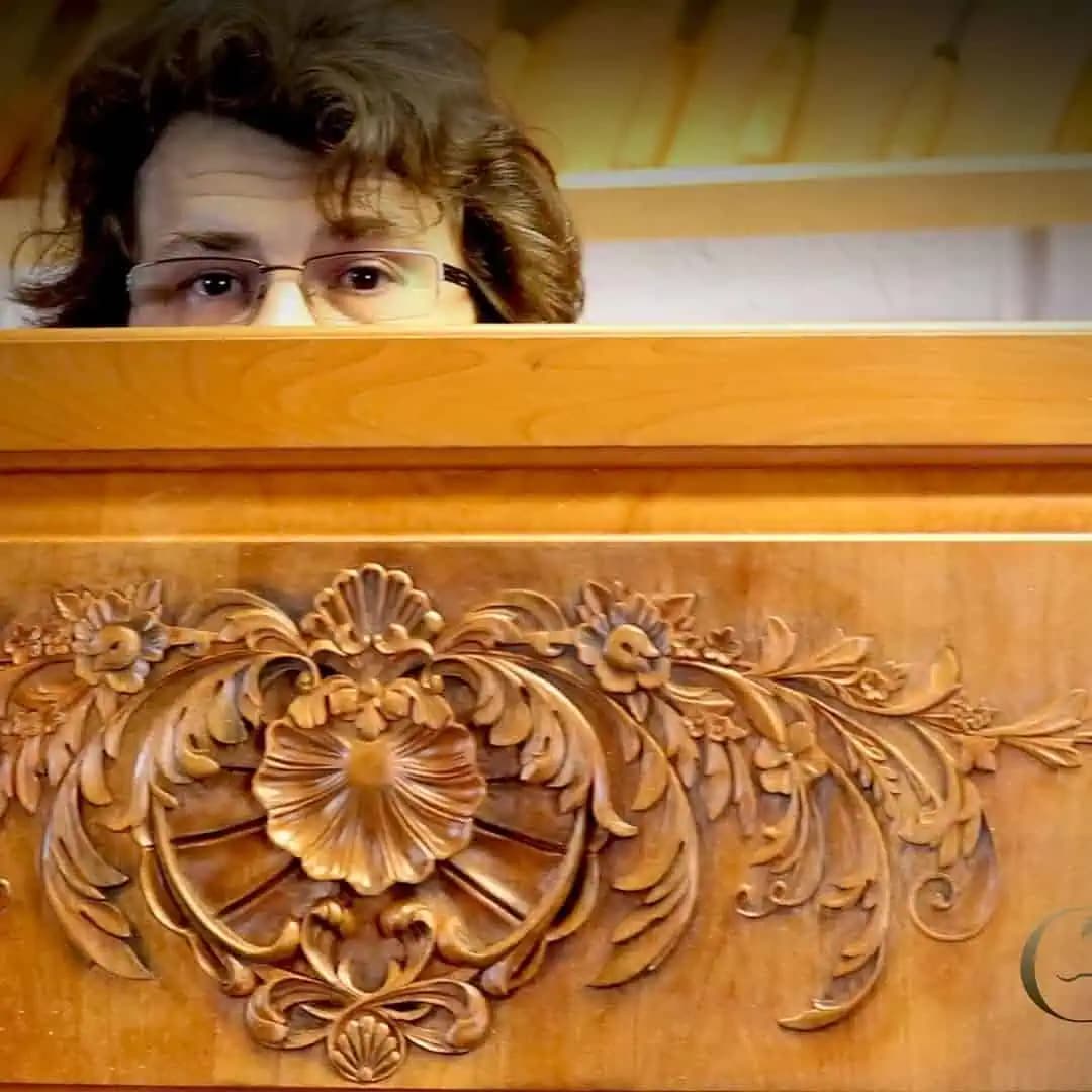 Carved Floral Cartouche Relief Panel Master carver Alexander Grabovetskiy behind a custom wood carving with a central floral rosette and scrolling foliage.